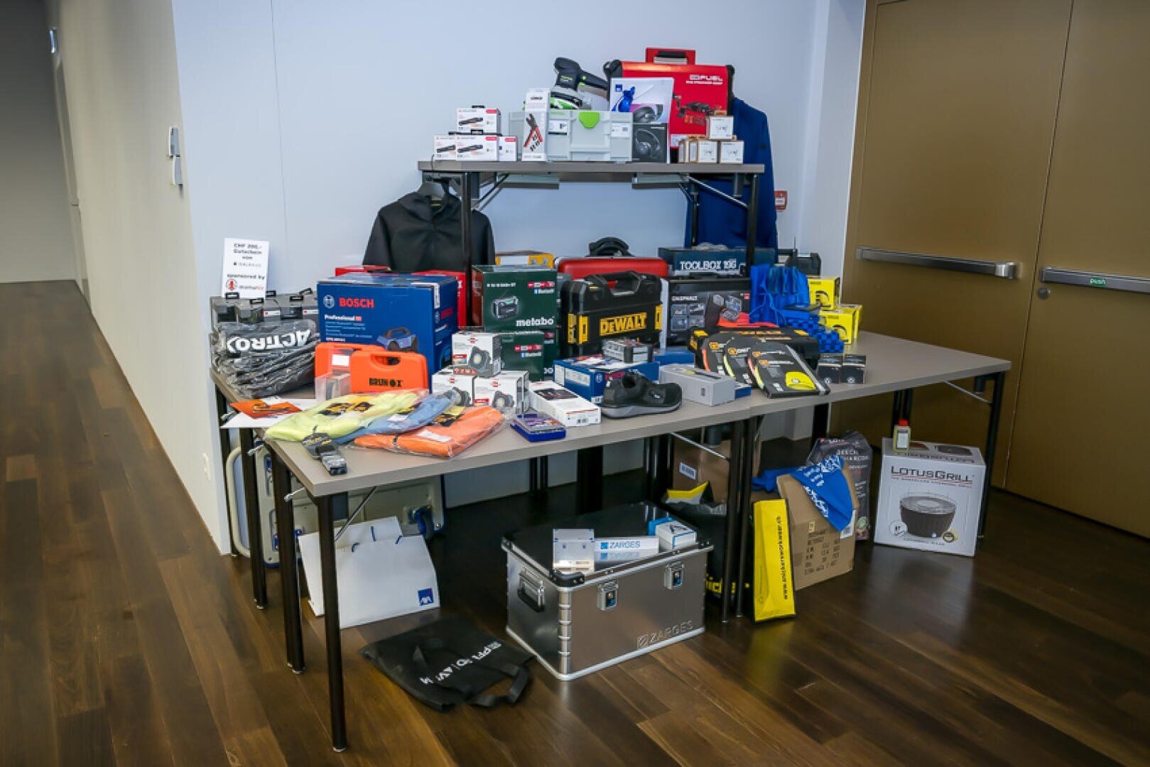 Ein Ausstellungs-Tisch, auf dem verschiedene Elektrowerkzeuge, Werkzeugkoffer und Markenartikel ausgestellt sind.