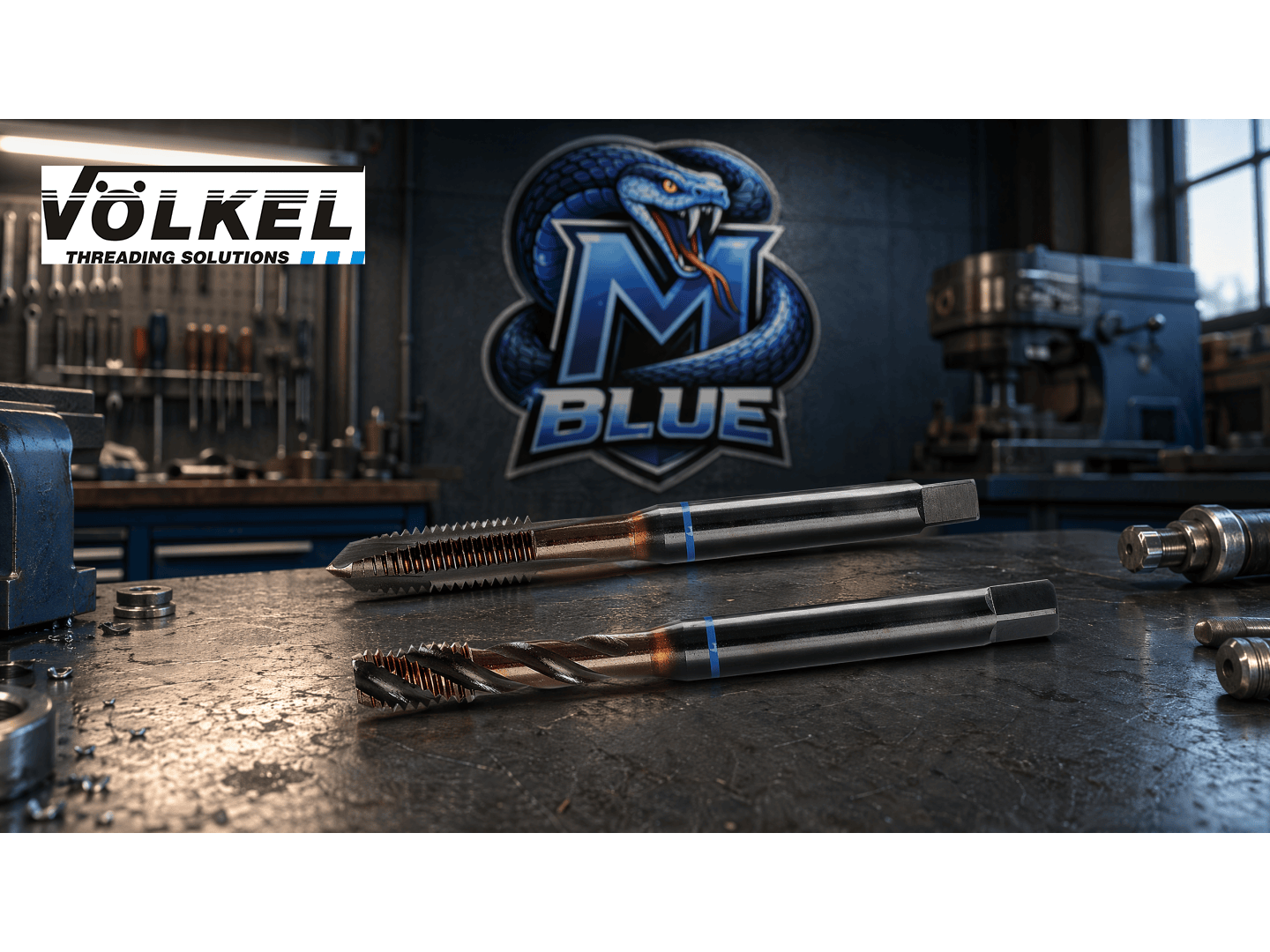 Deux tarauds à métaux sont exposés sur un établi dans un atelier. En arrière-plan, on peut voir un logo avec un serpent bleu et l'inscription M Blue, ainsi que le logo de Völkel Threading Solutions dans le coin supérieur gauche.