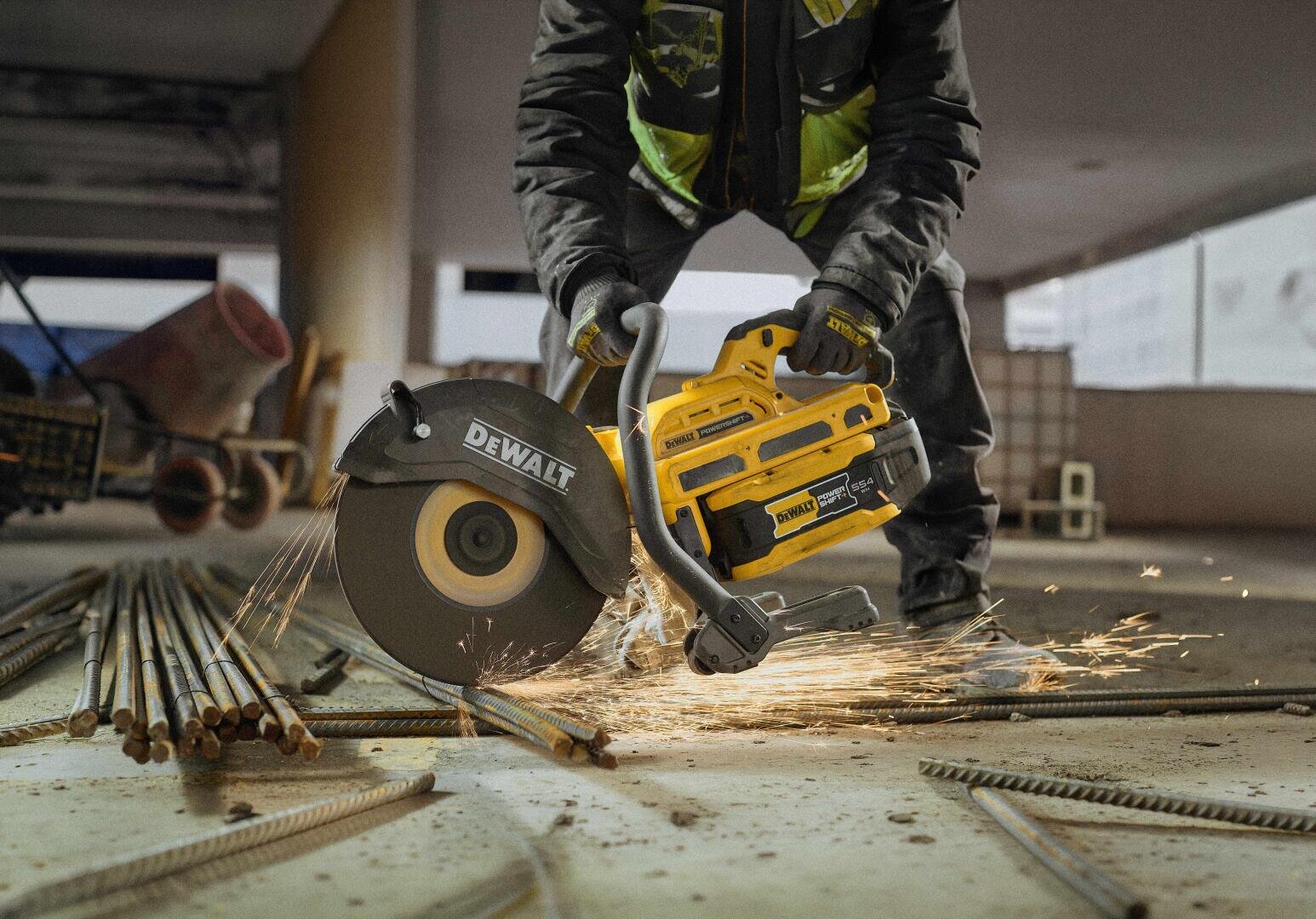 Ein Arbeiter schneidet mit einer DeWalt-Handtrennsäge Bewehrungsstahl auf einem Betonboden durch, wobei Funken in die Luft sprühen.