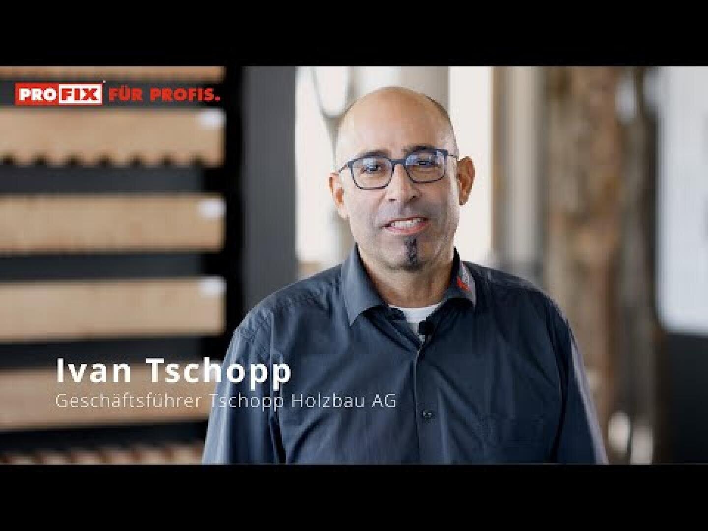Un homme portant des lunettes et une barbichette sourit à la caméra. Sur la photo, on peut lire : « PROFIX POUR LES PROFESSIONNELS ». Ivan Tschopp, directeur général de Tschopp Holzbau AG. L'arrière-plan est flou.